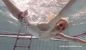 Štíhlá blonďatá dívka plave pod vodou
